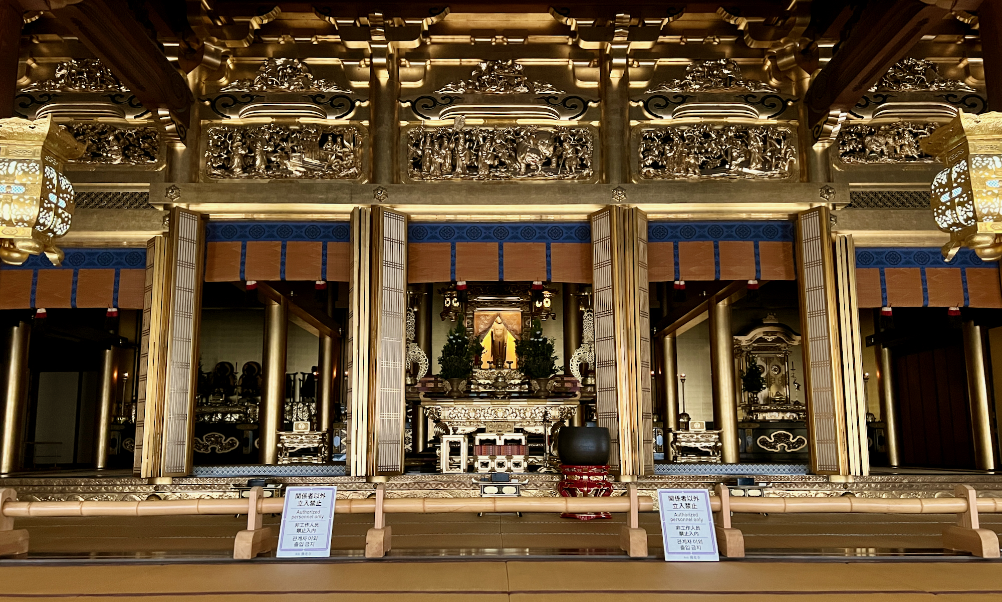 wide angle photo of a Japanese temple altar with a statue of Amida buddha in the center